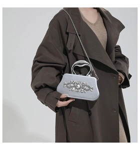 Silver evening box clutch with rhinestone floral patterns shown on a brown coat