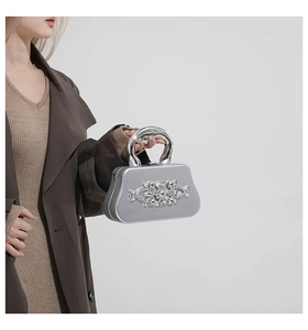 Detail of silver box clutch evening bag featuring sparkling rhinestones and metal handle