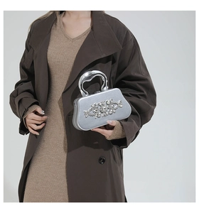 Silver hardshell evening clutch bag featuring floral rhinestone details and metallic handle
