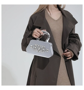Detail of silver evening clutch featuring crystal clusters and a curved metal handle