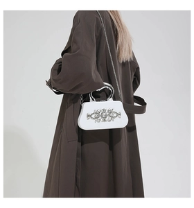Detail of white evening box bag with sparkling crystals and silver curved metal handle