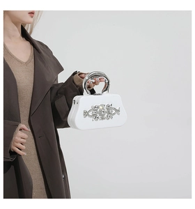 Close-up of elegant white box clutch with silver floral rhinestones and metal handle