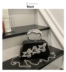 Detail of black hard shell evening bag with rhinestone flowers and silver metal handle