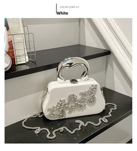 Macro detail of white evening clutch bag featuring silver rhinestone floral embellishments