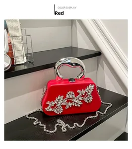 Detailed view of a red rhinestone evening clutch with silver metal handle and chain strap