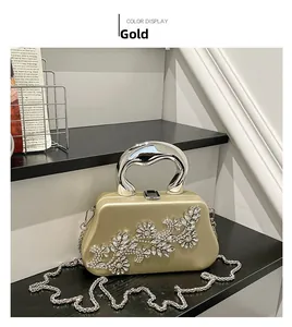 Detail of gold rhinestone evening bag with silver metal handle and chain on black stand