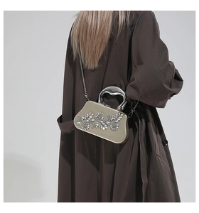 Detail of champagne gold evening clutch with 3D crystal floral patterns and metal handle