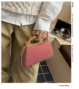 Detail of red rhinestone evening clutch bag with gold metal handle and luxury velvet finish
