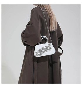 Detail of white evening clutch with silver rhinestone flower and U-shaped metal handle