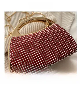 Macro shot of sparkling silver rhinestones and gold semi-circular handle on the red bag
