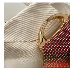 Detail of gold metal hook and lobster clasp on red rhinestone evening handbag