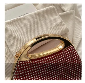 Detail of red rhinestone evening bag with elegant gold metal handle and satin fabric