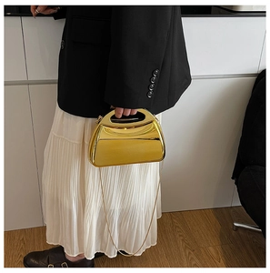 Fashionable gold metallic clutch with sleek chain strap shown on model with black blazer