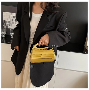 Close-up of modern gold metallic semi-moon handbag with sleek chain and cutout handle