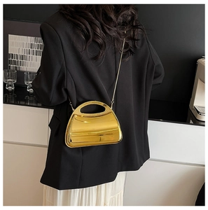 Golden acrylic evening bag with metallic finish shown on model with chain strap