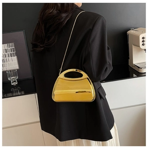 Detail of a mini gold mirror hard shell acrylic handbag with metal chain and top handle
