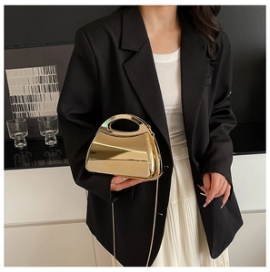 Detailed view of shiny gold metallic clutch bag with polished finish and detachable chain