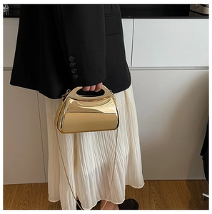 Close-up of golden mirrored metal handbag with elegant chain strap for evening wear