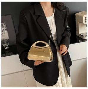Close-up of golden mirror finish acrylic handbag with delicate chain strap on model