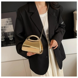 Close-up of golden mirror hard-shell handbag with metal handle and elegant chain strap
