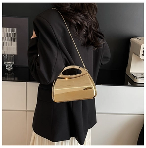 Close-up of golden mirrored acrylic handbag with metallic chain strap on a model