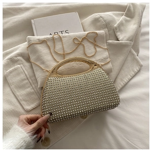 Close-up of sparkling rhinestone handbag with golden ring handle and fine chain strap