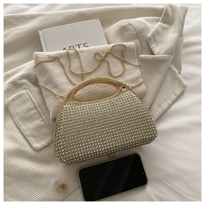 Detail of evening clutch bag with sparkling white rhinestones and gold metal handle
