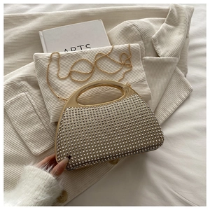 Detail of a semicircular evening bag with silver rhinestones and a gold metal handle