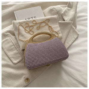 Detail of lilac rhinestone clutch bag with gold handle and chain on white suit jacket