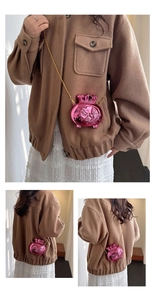 Macro detail of metallic pink lucky bag crossbody bag with koi relief and gold chain