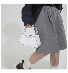 Macro shot of white leather handbag featuring silver studs and metallic handle detail