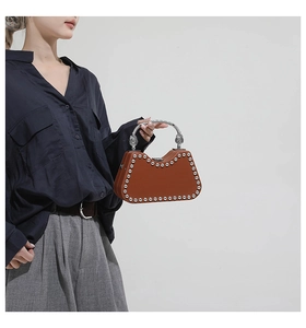 Detailed view of brown structured handbag with silver studs and engraved metal handle