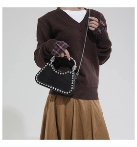 Detail of black matte handbag featuring silver studs and metallic ring handle with lion head
