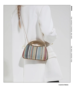 Bunte gewebte Muscheltasche mit goldener Kette auf einem weißen Blazer-Outfit