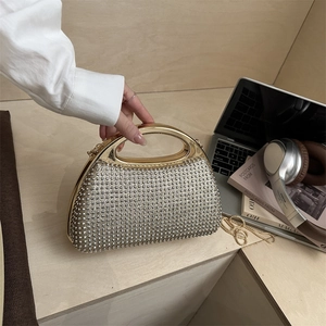 Elegant rhinestone evening clutch with metal ring handle and chain strap on desk