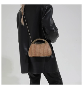 Detail einer handgewebten Strohtasche mit halbrundem Goldgriff und feinem Kettenriemen