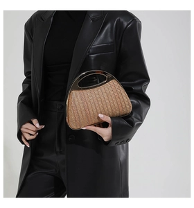 Nahaufnahme der halbrunden Strohhandtasche mit goldenem, hohlem Metallgriff