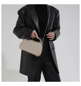 Detailansicht der Stroh-Handtasche mit goldenem Halbkreisgriff und Metallkettenriemen