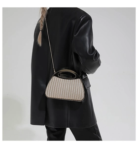Detail der gewebten Muscheltasche mit schwarzem Griff und goldener Metall-Kettenriemen