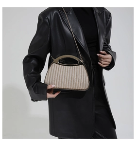 Detailaufnahme einer gewebten Muschel-Clutch mit goldenen Griffen und einer feinen Kette
