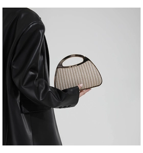 Detail einer gewebten muschelförmigen Handtasche mit Goldgriff und vertikaler Rippenstruktur