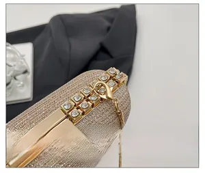 Detail of the champagne gold clutch featuring a rhinestone clasp and sleek snake chain strap