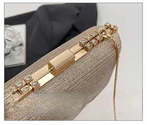 Detail of champagne gold glitter clutch featuring a rhinestone-inlaid metal push-lock closure