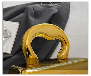 Detail of the unique wavy gold handle on a glossy metallic evening acrylic clutch bag