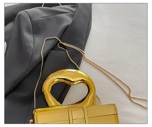 Detail of elegant gold metal handbag with a sturdy circular handle and fine chain strap
