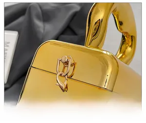 Macro detail of the golden mirror acrylic box bag featuring heart-shaped metal handle and chain