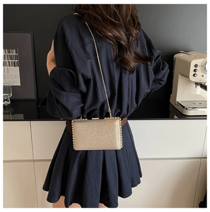 Detail of a sparkling gold glitter clutch bag with elegant metal chain strap for women
