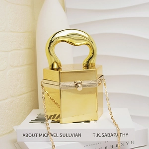 Detailansicht einer sechseckigen goldenen Acryl-Clutch mit Metallgriff und eleganter Kette