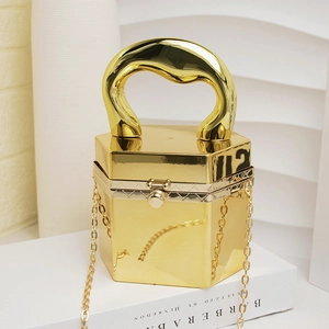 Detailaufnahme der goldenen Acryl-Abendtasche mit skulpturalem Metallgriff und Kette