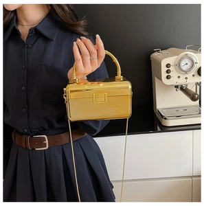 Detail of gold mirror metal clutch box bag with bamboo style handle and chain strap